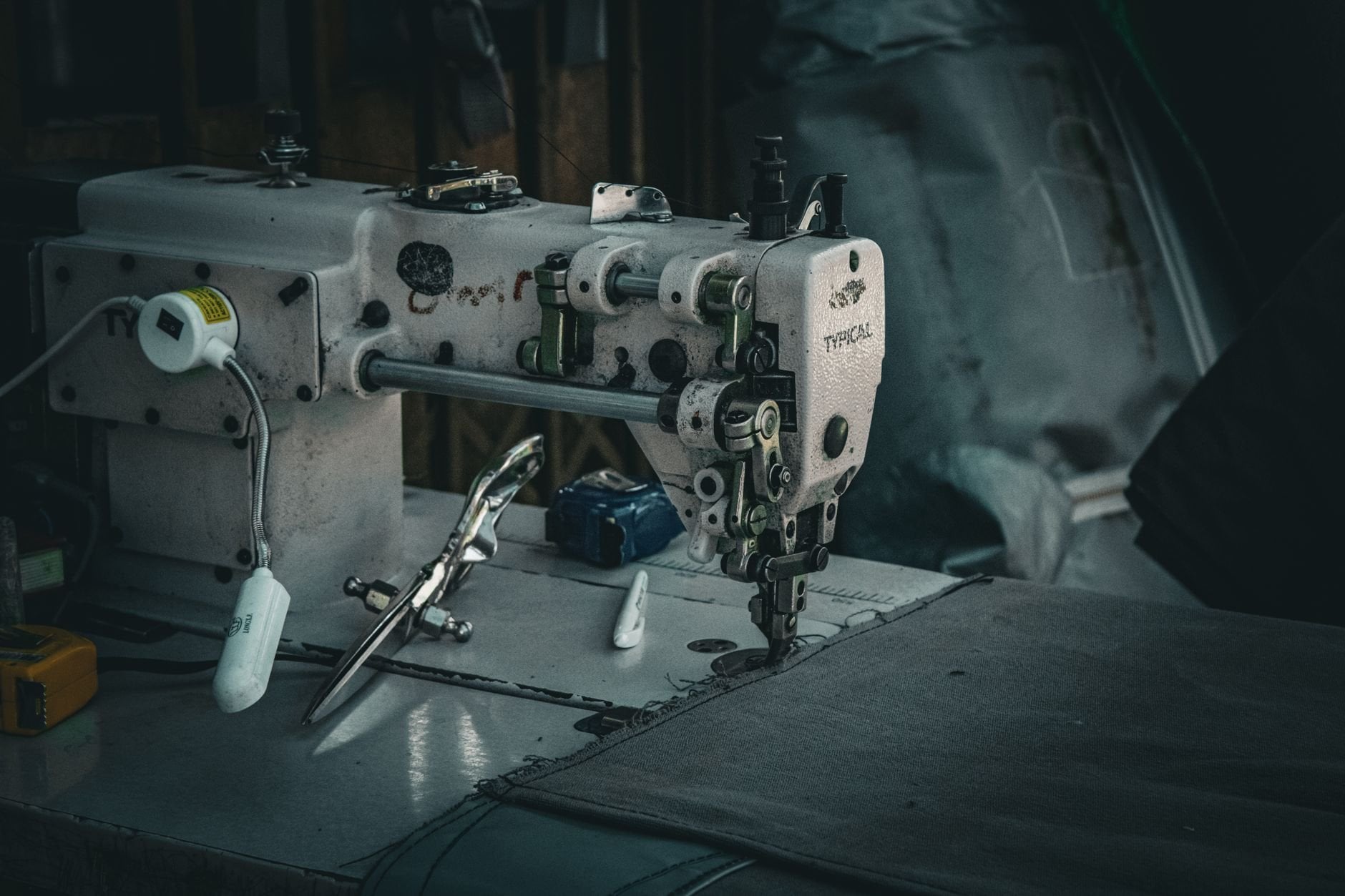 A vintage industrial sewing machine in a dimly lit workshop, showcasing intricate details and craftsmanship.