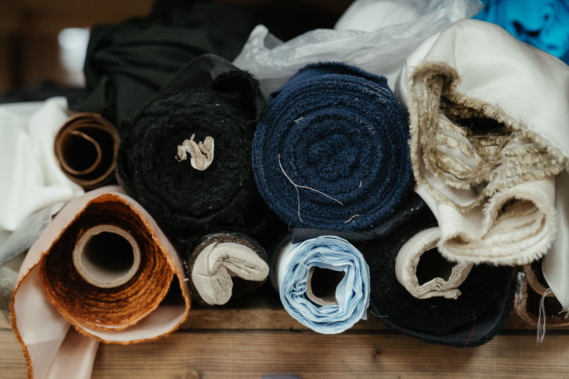 A close-up of various fabric rolls in a workshop, showcasing textures and colours.